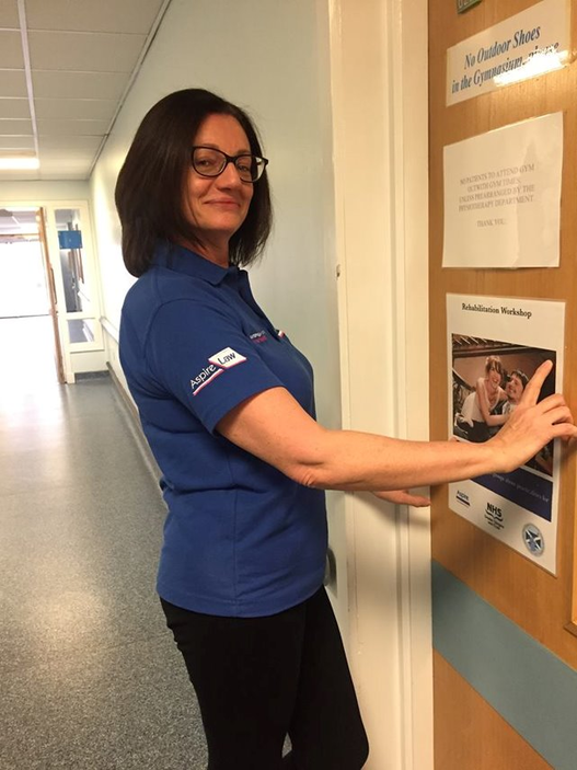 An image of a woman with brown hair and glasses wearing a blue 'Aspire' polo shirt.